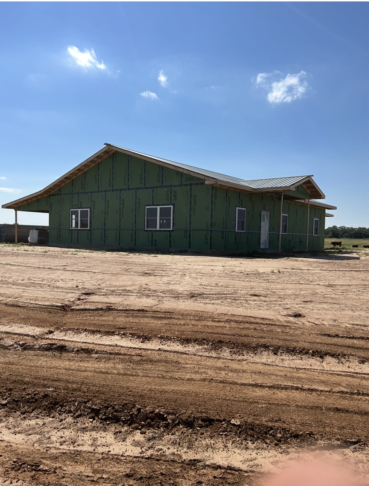 New home under construction with exterior sheathing, a roof, and windows installed